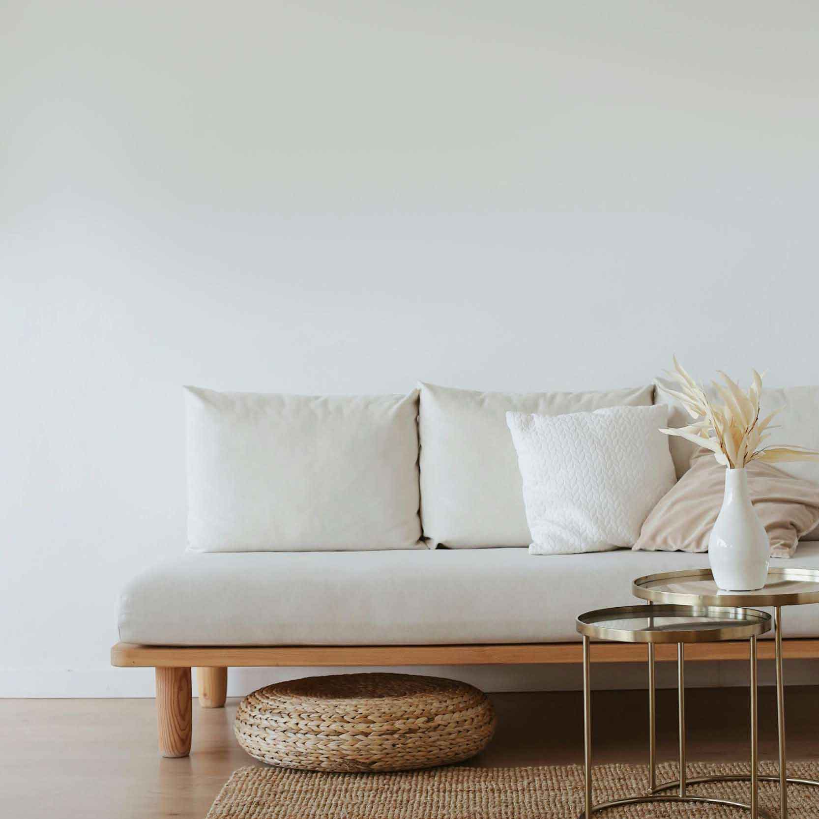 A white couch positioned in a room featuring a matching white wall, creating a minimalist and serene atmosphere